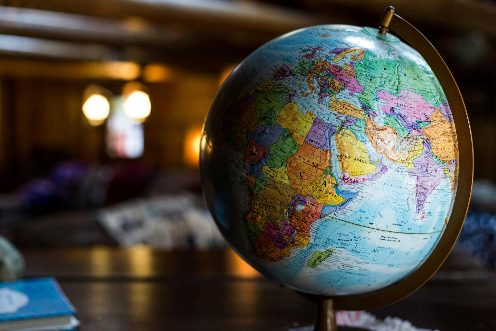 A globe turned to display the Middle East and Central / West Asia sitting on a wood desk in a wood-paneled room.